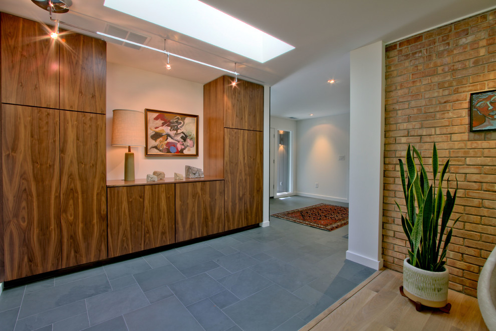 Ispirazione per un grande ingresso con vestibolo minimalista con pareti bianche, pavimento in ardesia e pavimento grigio