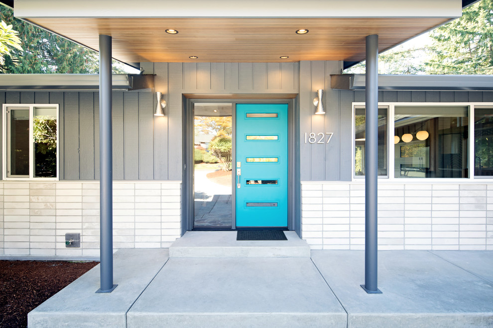 Exempel på en mellanstor 50 tals ingång och ytterdörr, med grå väggar, betonggolv, en enkeldörr, en blå dörr och grått golv