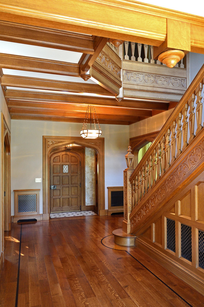 Inspiration pour un grand hall d'entrée traditionnel avec un mur beige, un sol en bois brun, une porte simple et une porte en bois brun.
