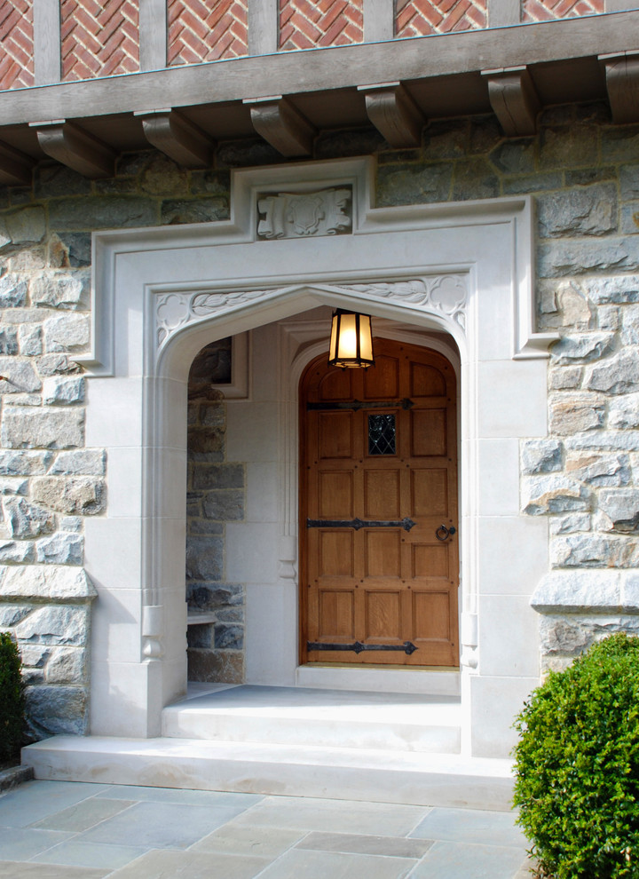 Ejemplo de entrada clásica grande con puerta simple y puerta de madera en tonos medios