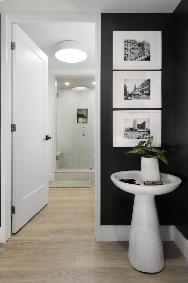 Foto på en liten 60 tals foajé, med svarta väggar, ljust trägolv, en enkeldörr, en vit dörr och beiget golv