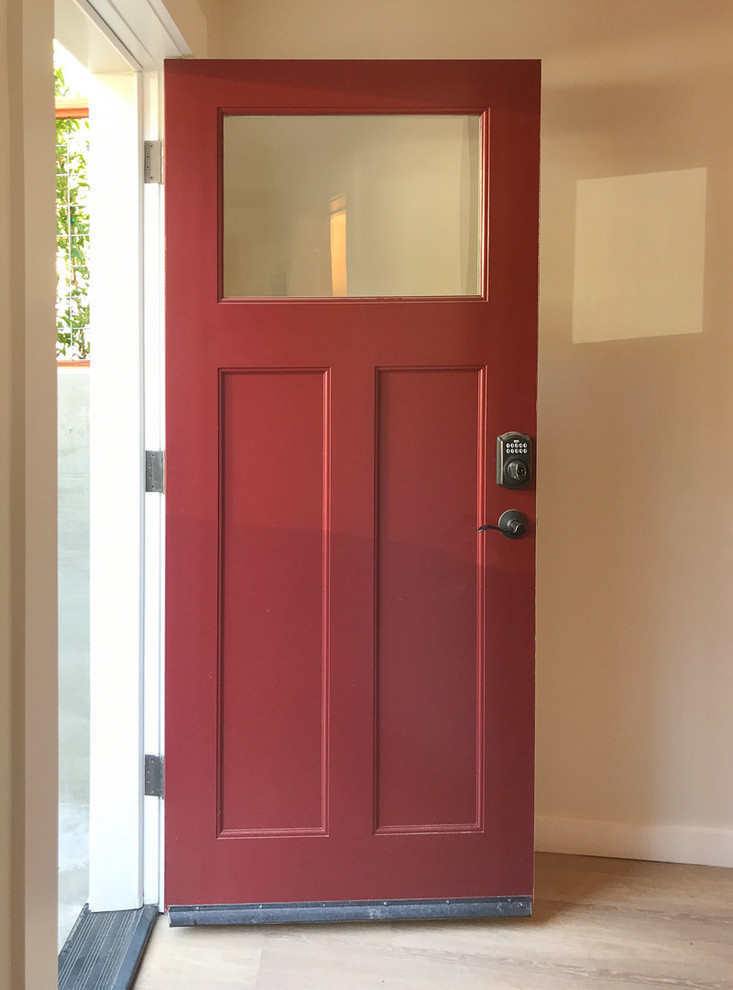 Immagine di un ingresso o corridoio minimalista con pareti bianche, parquet chiaro, una porta rossa e pavimento beige