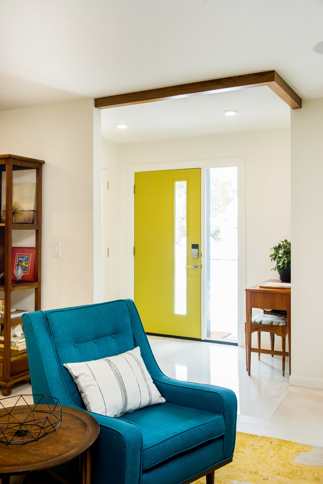 Bild på en liten retro ingång och ytterdörr, med vita väggar, ljust trägolv, en enkeldörr och en gul dörr