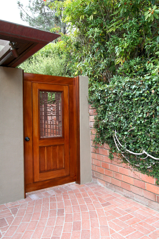 Diseño de entrada retro con suelo de ladrillo y puerta de madera en tonos medios