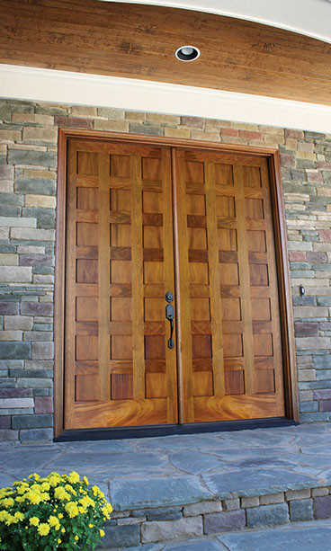 Ejemplo de puerta principal contemporánea de tamaño medio con paredes marrones, suelo de ladrillo, puerta doble y puerta de madera clara
