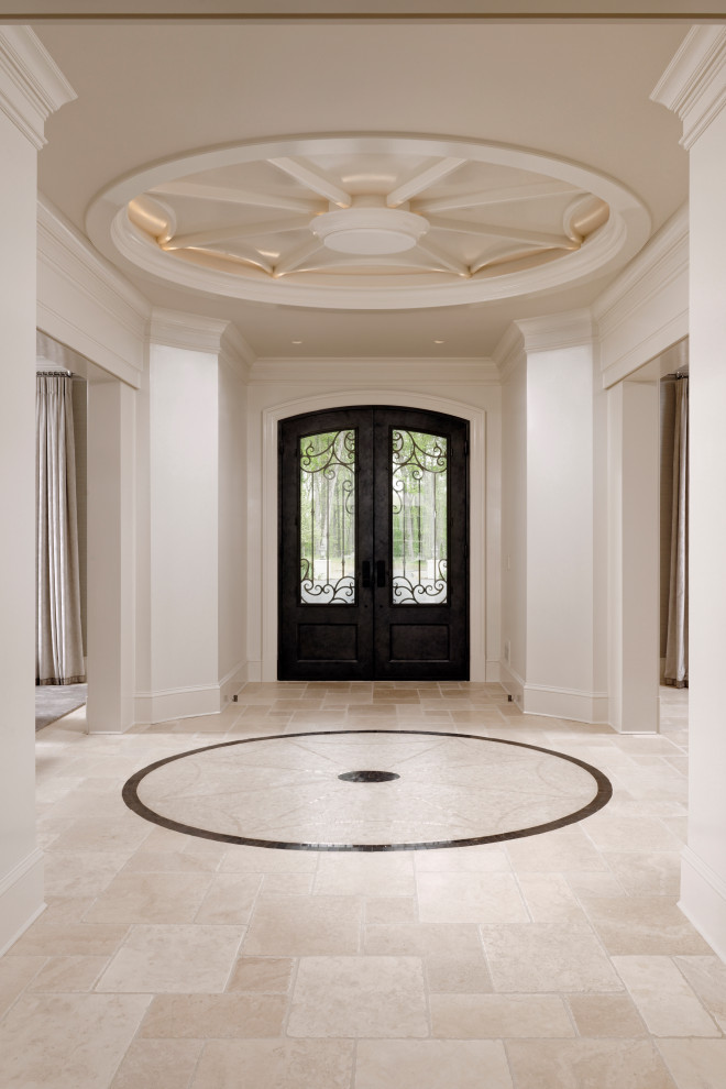 Пример оригинального дизайна: большая входная дверь в стиле неоклассика (современная классика) с белыми стенами, полом из известняка, двустворчатой входной дверью, входной дверью из темного дерева, бежевым полом и кессонным потолком