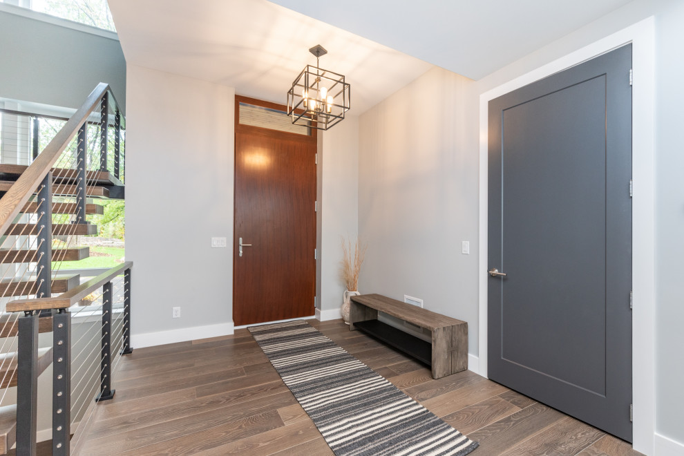 Photo of a medium sized modern front door in Minneapolis with grey walls, light hardwood flooring, a single front door, a dark wood front door and brown floors.