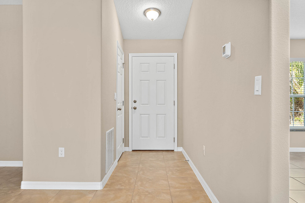 Entryway - mid-sized traditional ceramic tile and beige floor entryway idea in Orlando with beige walls and a white front door