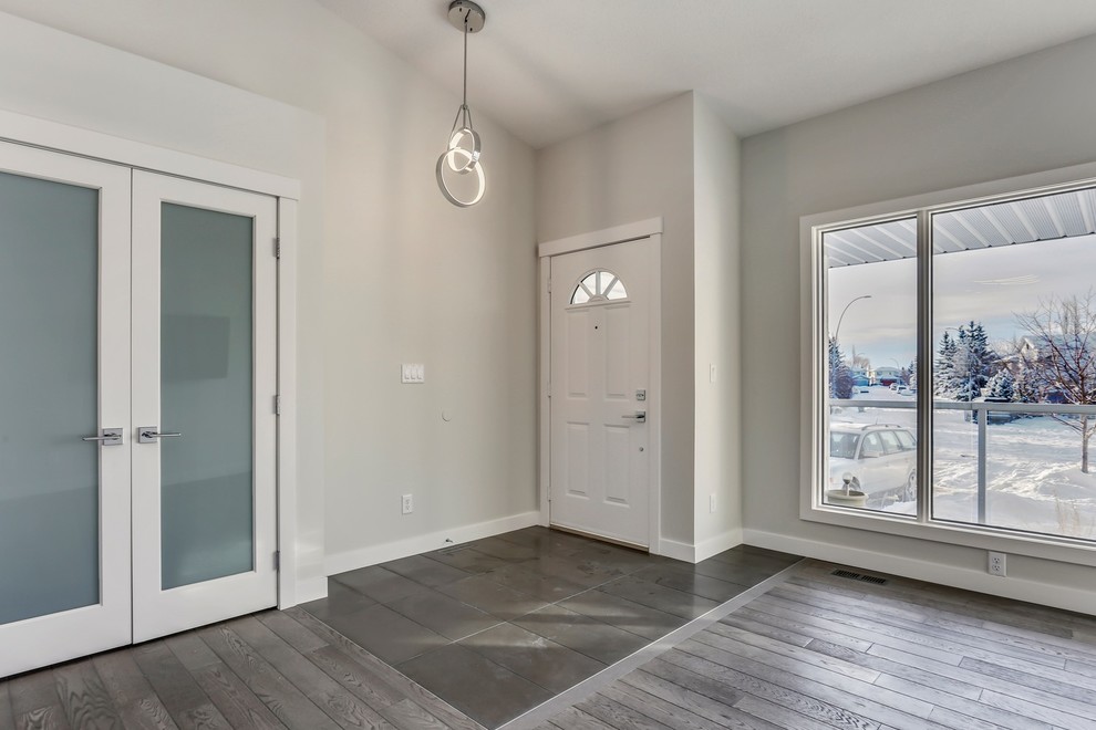 Photo of a medium sized classic front door in Calgary with white walls, medium hardwood flooring, a single front door, a white front door and brown floors.