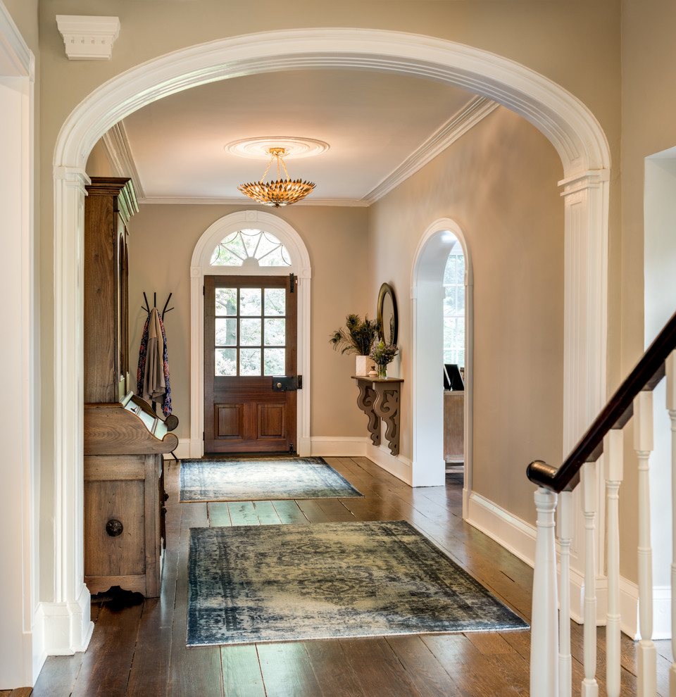 This is an example of a large farmhouse foyer in Philadelphia with beige walls, a single front door, a dark wood front door, brown floors and dark hardwood flooring.