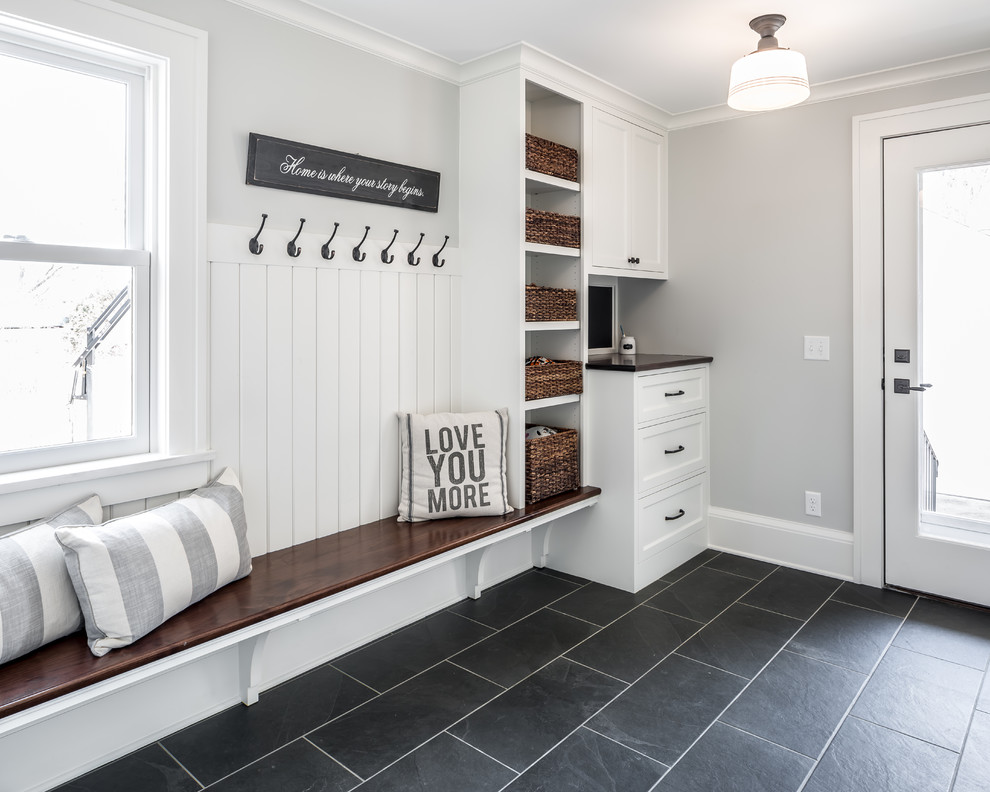 This is an example of a country boot room in Minneapolis with grey walls, a single front door, a glass front door and black floors.