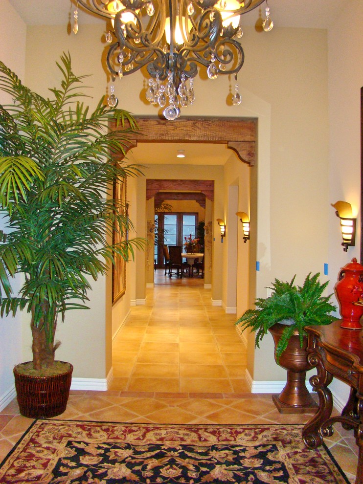 Immagine di un corridoio mediterraneo di medie dimensioni con pareti beige, pavimento in terracotta, una porta singola, una porta in legno bruno e pavimento beige