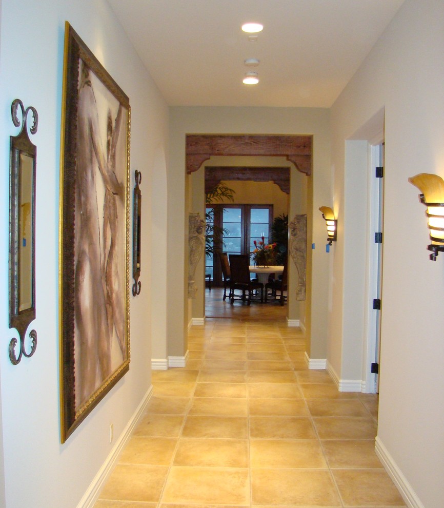 Immagine di un corridoio mediterraneo di medie dimensioni con pareti beige, pavimento in terracotta, una porta singola, una porta in legno bruno e pavimento beige