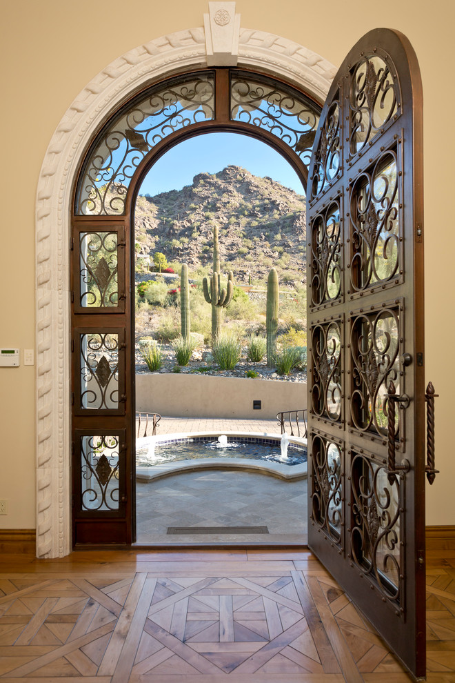 Imagen de puerta principal mediterránea extra grande con paredes beige, suelo de piedra caliza, puerta simple y puerta de madera oscura