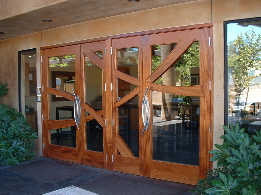 Réalisation d'une grande porte d'entrée design avec un mur beige, une porte double et une porte en bois brun.