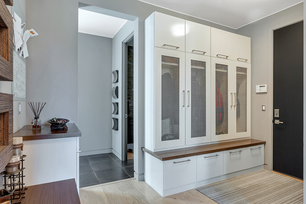 Photo of a large contemporary boot room in Minneapolis with grey walls, light hardwood flooring, a single front door and a black front door.