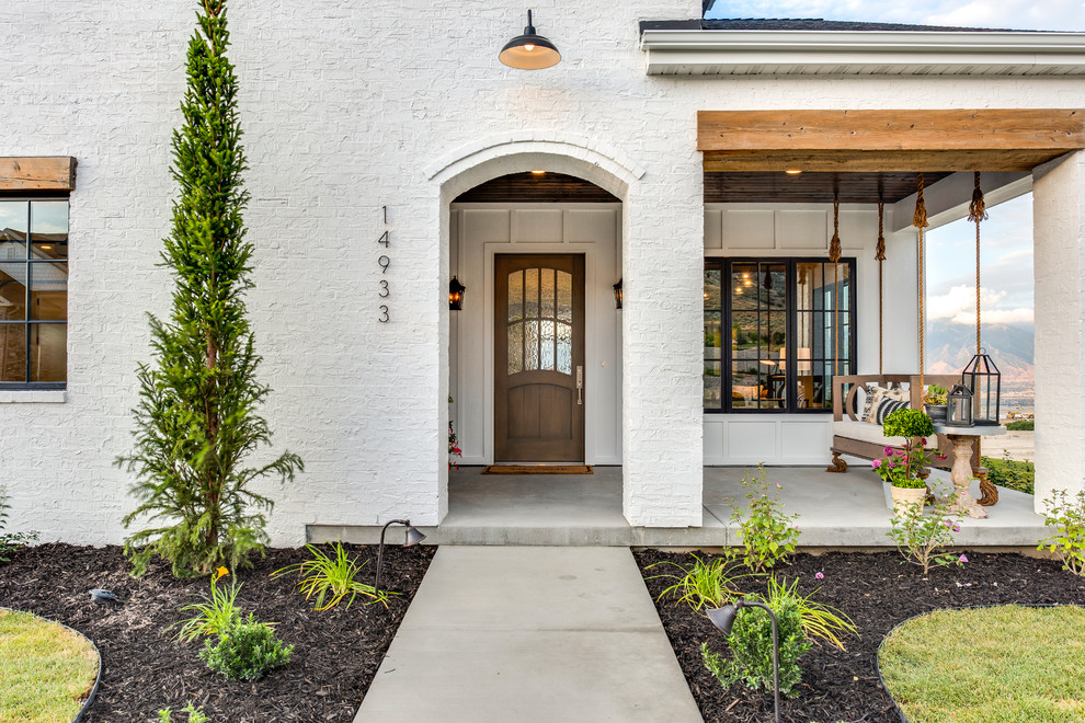 Diseño de puerta principal de estilo de casa de campo con paredes blancas, suelo de cemento, puerta simple, puerta de madera en tonos medios y suelo gris