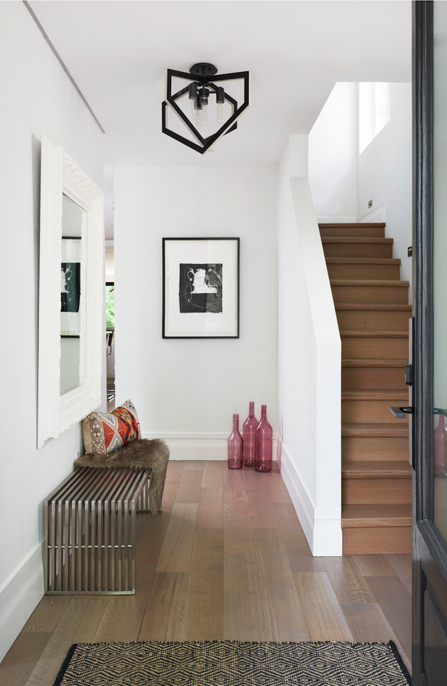 Diseño de entrada contemporánea con paredes blancas, suelo de madera en tonos medios, puerta simple, puerta negra y suelo marrón