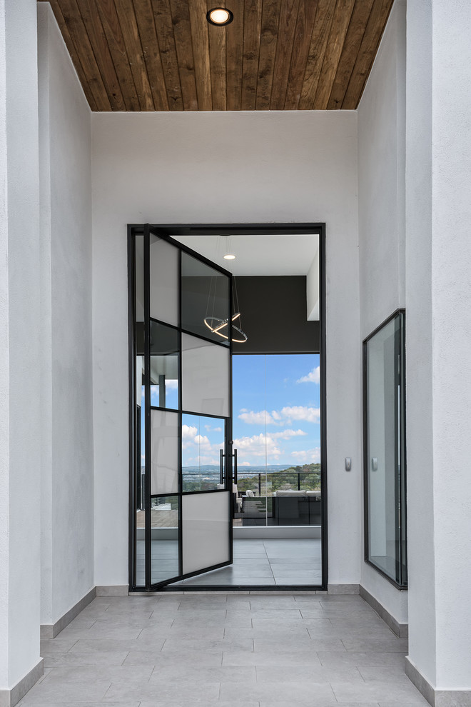 На фото: входная дверь в современном стиле с поворотной входной дверью и стеклянной входной дверью с