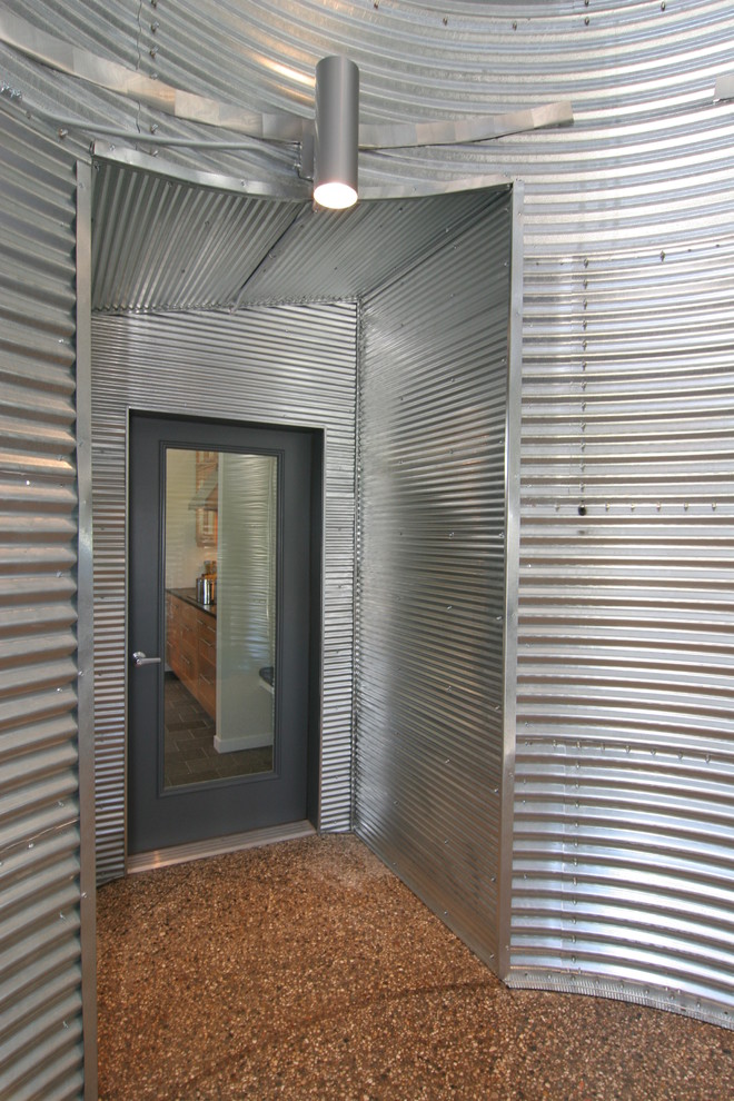 Réalisation d'un vestibule urbain de taille moyenne avec mur métallisé, sol en béton ciré, une porte simple et une porte grise.