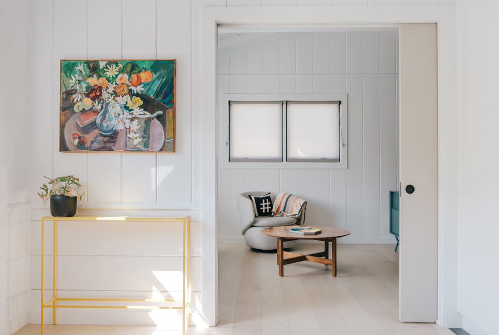 Kleines Foyer mit weißer Wandfarbe, hellem Holzboden, Klöntür, Haustür aus Glas, beigem Boden, freigelegten Dachbalken und Wandpaneelen in Orange County