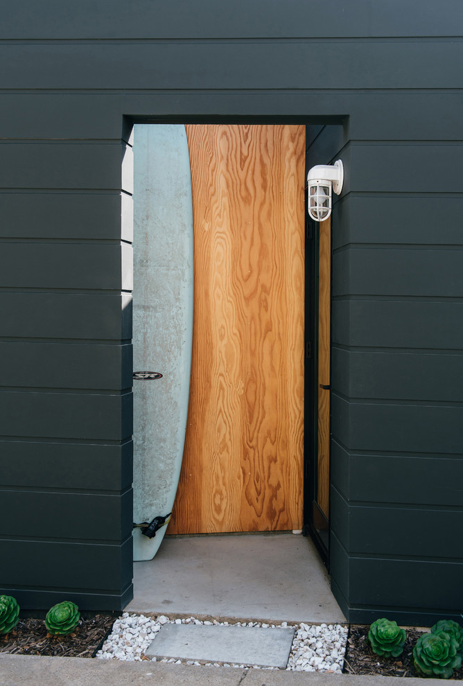Kleiner Maritimer Eingang mit Vestibül, schwarzer Wandfarbe, Betonboden, Einzeltür, hellbrauner Holzhaustür und grauem Boden in Orange County