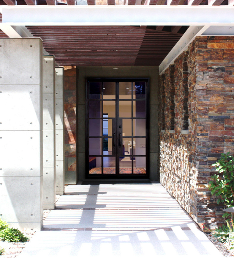 На фото: большая входная дверь в современном стиле с коричневыми стенами, полом из известняка, двустворчатой входной дверью и стеклянной входной дверью с
