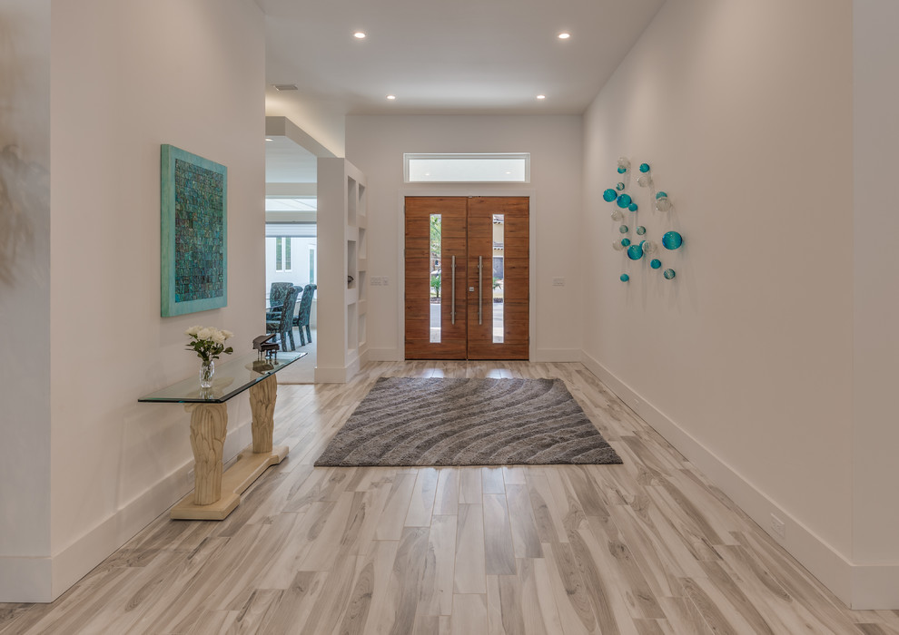 Example of a large trendy porcelain tile and gray floor entryway design in Jacksonville with white walls and a medium wood front door
