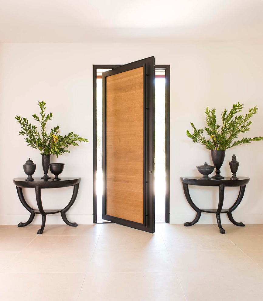 Idée de décoration pour une entrée design avec un mur blanc, une porte pivot, une porte en bois brun et un sol beige.
