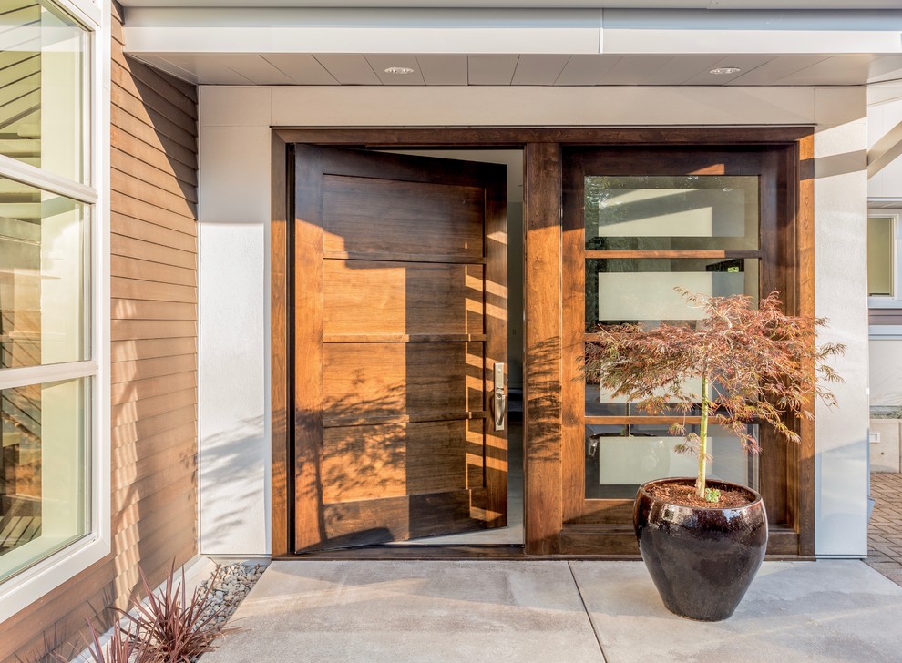Große Moderne Haustür mit hellbrauner Holzhaustür, weißer Wandfarbe, Betonboden, Drehtür und grauem Boden in Los Angeles