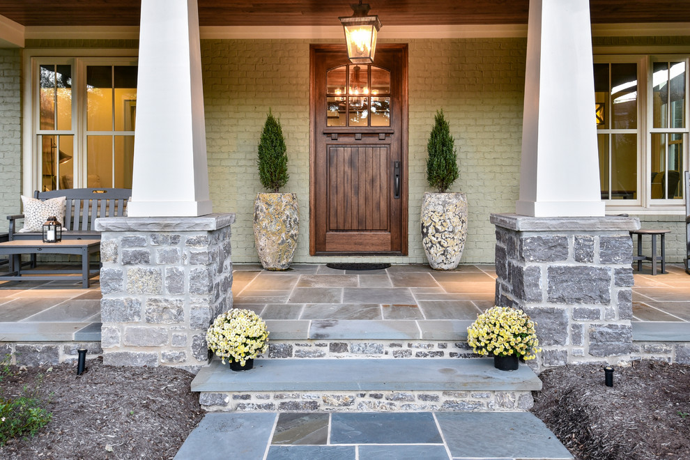 Aménagement d'une porte d'entrée craftsman avec un mur vert, une porte simple, une porte en bois brun et un sol gris.