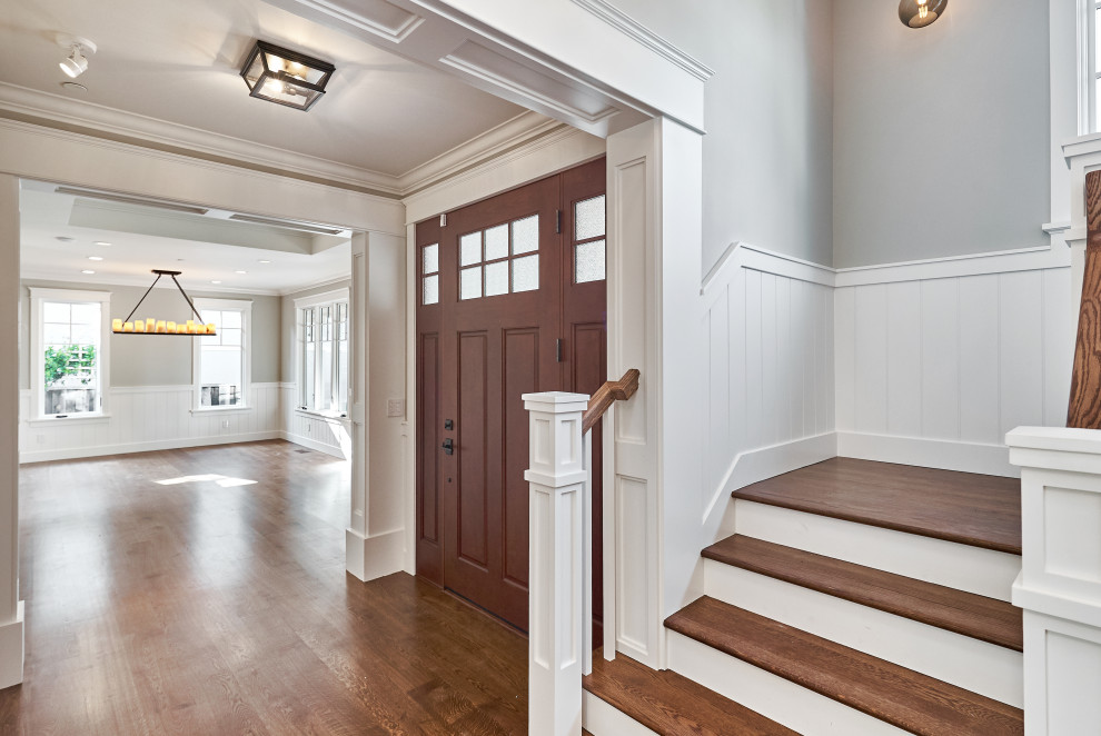 Modelo de puerta principal clásica de tamaño medio con paredes grises, suelo de madera en tonos medios, puerta simple, puerta de madera oscura y suelo marrón