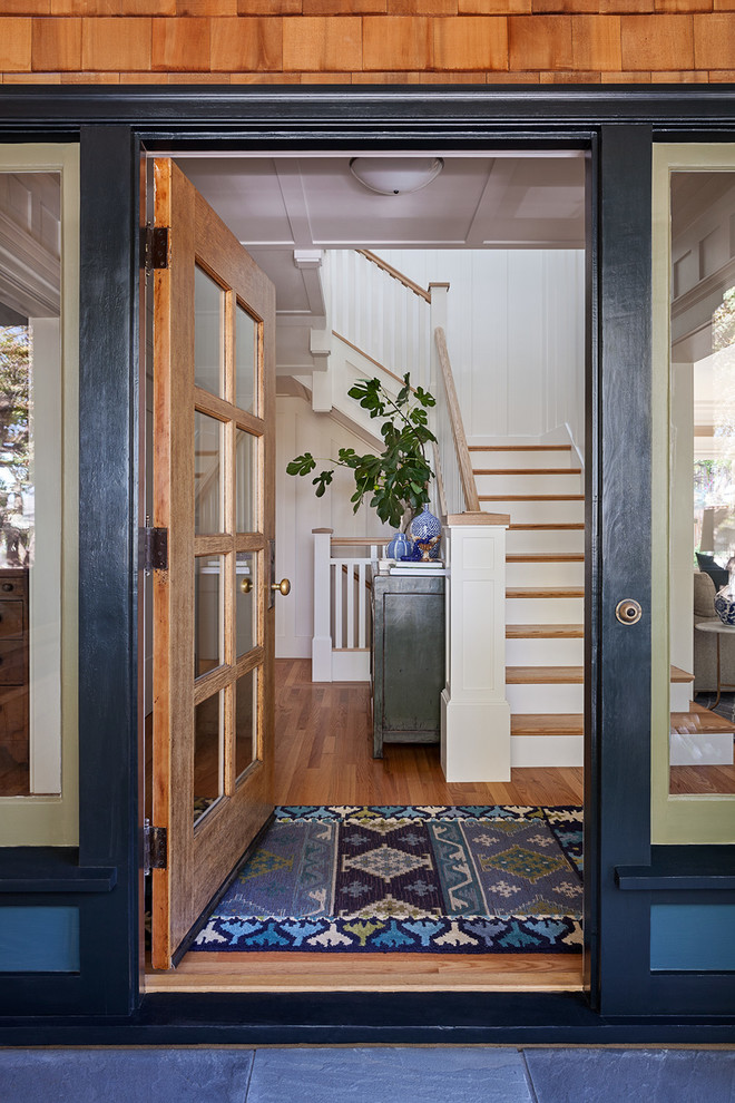Immagine di un ingresso stile americano di medie dimensioni con pareti bianche, pavimento in legno massello medio, una porta singola, una porta in vetro e pavimento marrone