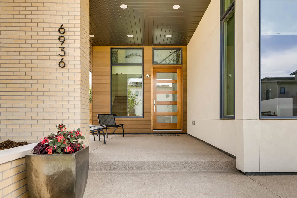 Bild på en funkis ingång och ytterdörr, med vita väggar, betonggolv, en enkeldörr, glasdörr och grått golv