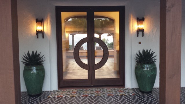 Стильный дизайн: входная дверь среднего размера в средиземноморском стиле с белыми стенами, двустворчатой входной дверью, металлической входной дверью, полом из керамогранита и коричневым полом - последний тренд