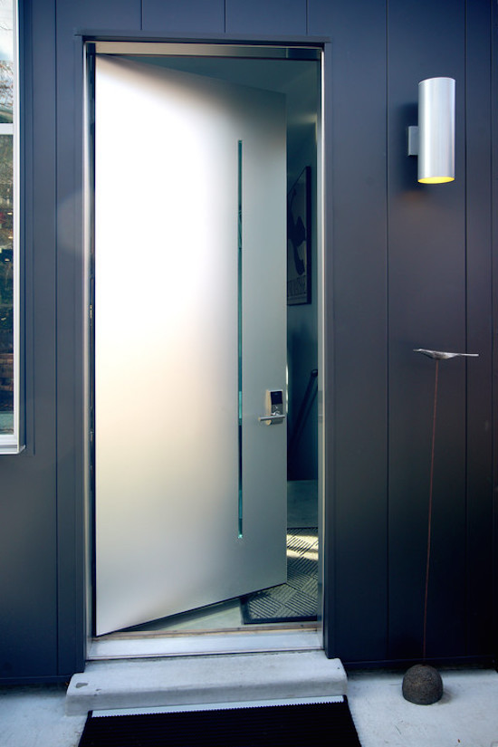 Diseño de puerta principal minimalista de tamaño medio con paredes blancas, suelo de cemento, puerta simple y puerta metalizada