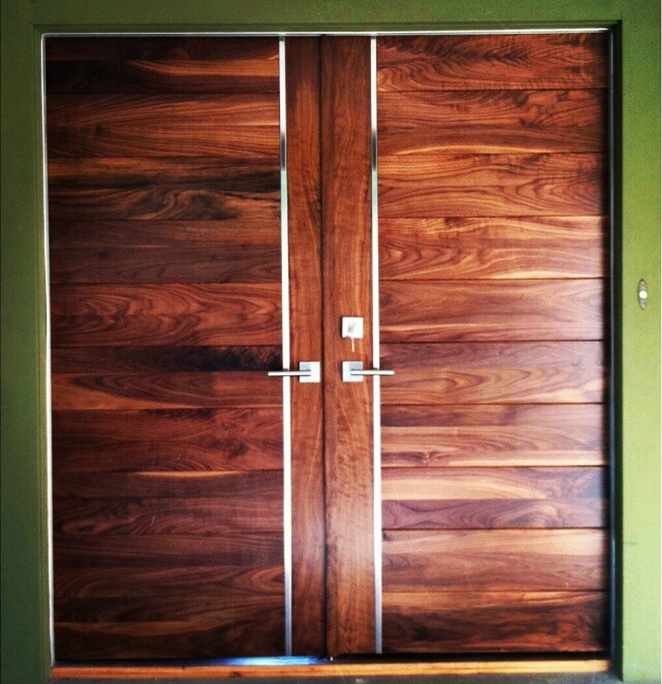 Cette image montre une grande porte d'entrée minimaliste avec une porte double, une porte en bois brun, un mur vert et parquet clair.