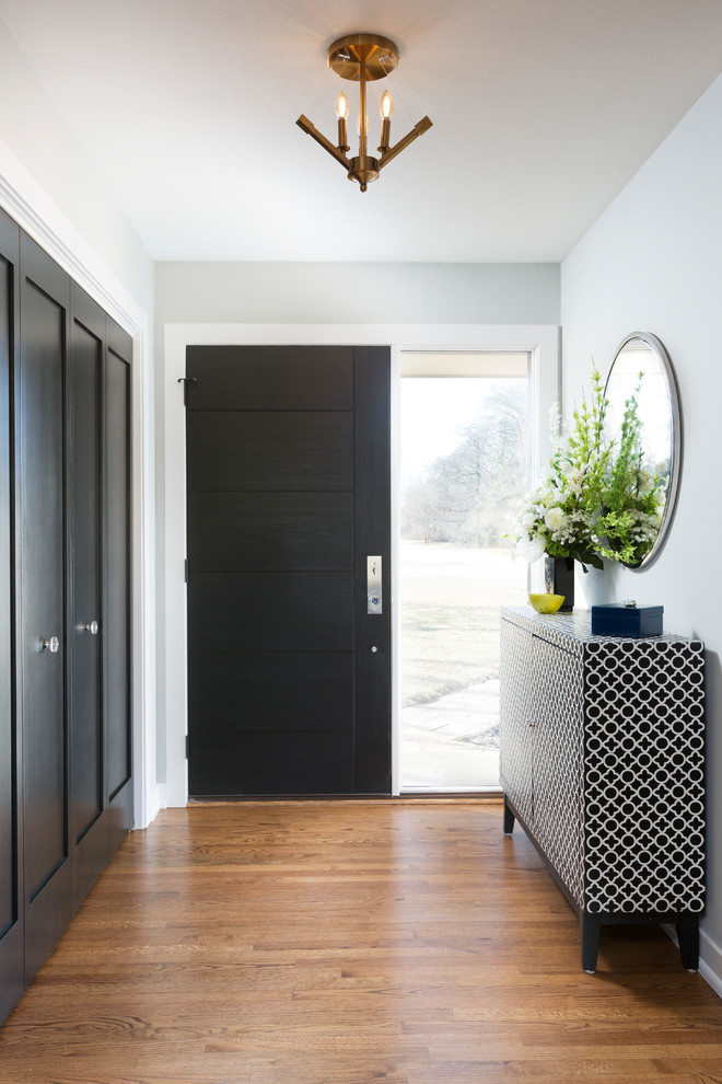 Réalisation d'un petit hall d'entrée minimaliste avec un mur vert, un sol en bois brun, une porte simple, une porte noire et un sol marron.
