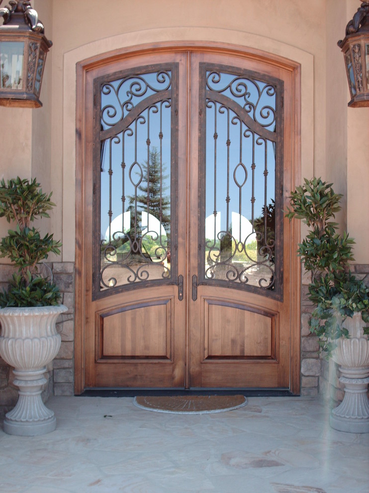 Modelo de puerta principal mediterránea grande con paredes beige, puerta doble y puerta de madera en tonos medios