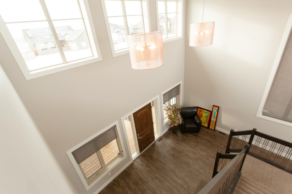 Réalisation d'un grand hall d'entrée minimaliste avec un mur beige, un sol en bois brun, une porte simple et une porte en bois foncé.