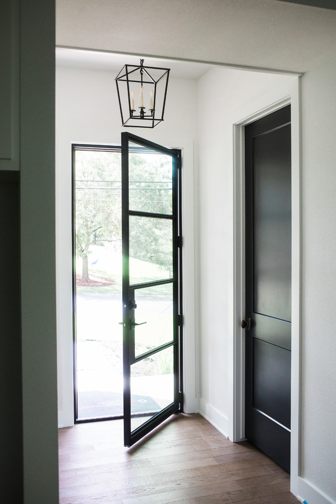 Foto di un piccolo ingresso country con pareti bianche, pavimento in legno massello medio, una porta singola, una porta in vetro e pavimento marrone