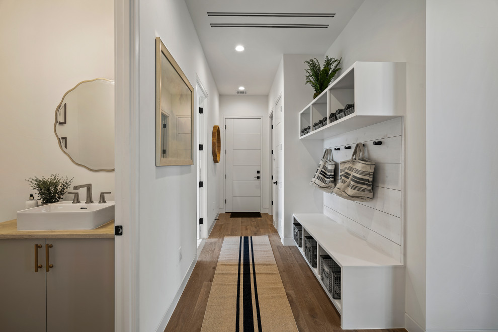 Landhausstil Eingang mit weißer Wandfarbe, dunklem Holzboden, Einzeltür, weißer Haustür und braunem Boden in Austin