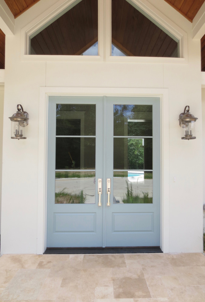 Réalisation d'une grande porte d'entrée minimaliste avec un mur blanc, un sol en travertin, une porte double, une porte bleue et un sol beige.