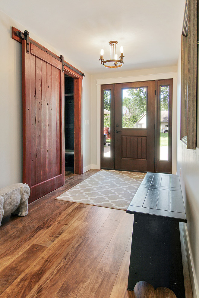 Idée de décoration pour un hall d'entrée champêtre avec un mur gris, un sol en vinyl, une porte simple, une porte en bois brun et un sol marron.