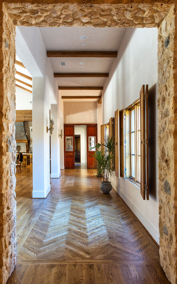 Cette image montre un hall d'entrée rustique de taille moyenne avec un mur blanc, un sol en bois brun, une porte simple et une porte en bois foncé.