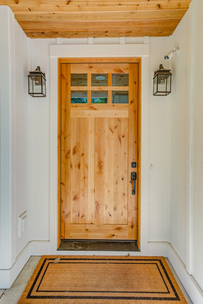 Immagine di una porta d'ingresso country di medie dimensioni con pareti bianche, una porta singola e una porta in legno chiaro