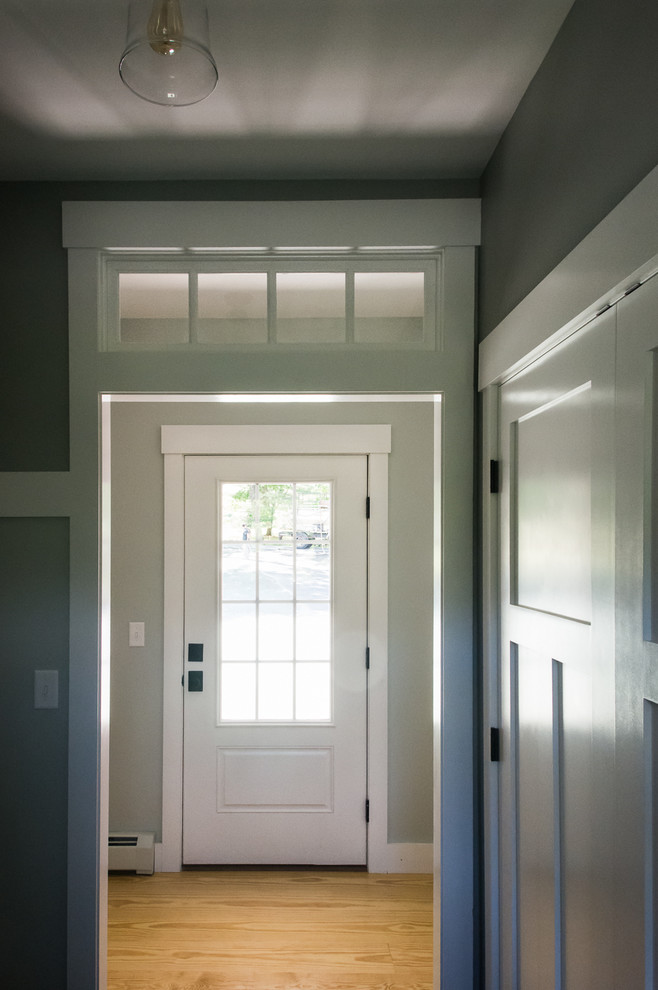 Example of a small cottage light wood floor and brown floor entryway design in Portland Maine with gray walls and a white front door