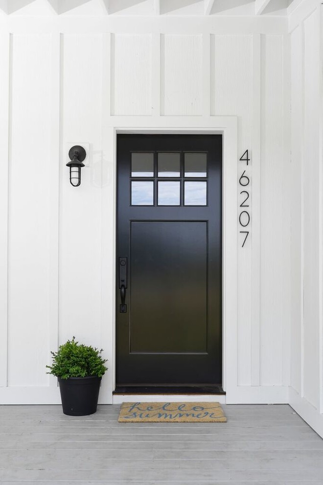 Cette image montre une porte d'entrée rustique avec une porte simple et une porte noire.