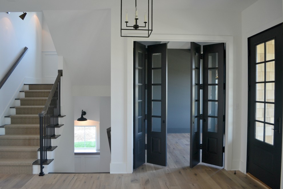 Foto de distribuidor de estilo de casa de campo de tamaño medio con paredes blancas, suelo de madera en tonos medios, puerta doble y puerta gris