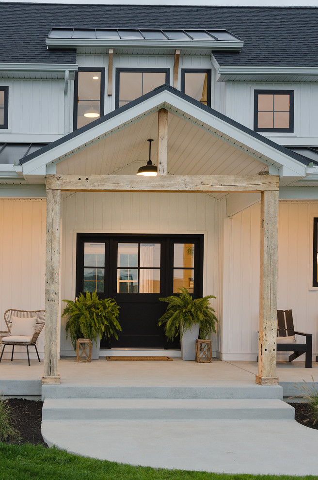 Diseño de puerta principal de estilo de casa de campo de tamaño medio con puerta negra, paredes blancas, suelo de cemento, puerta simple y suelo gris